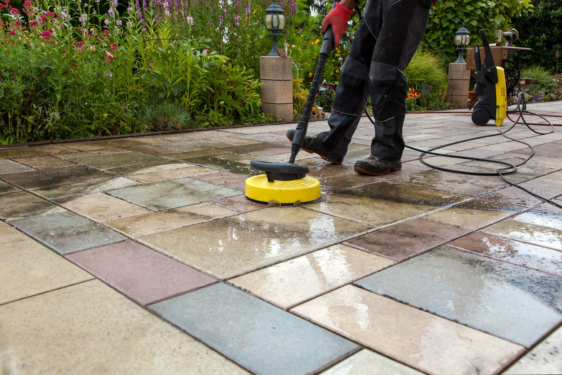 Cleaning stone slabs on patio with the high-pressure cleaner.